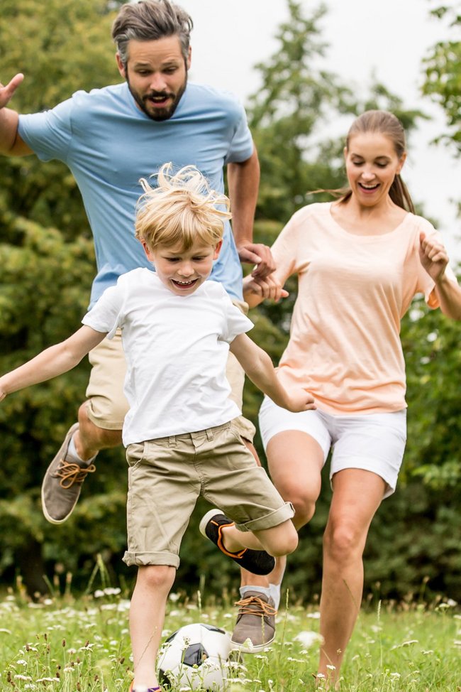 Familie spielt Fußball im Garten.