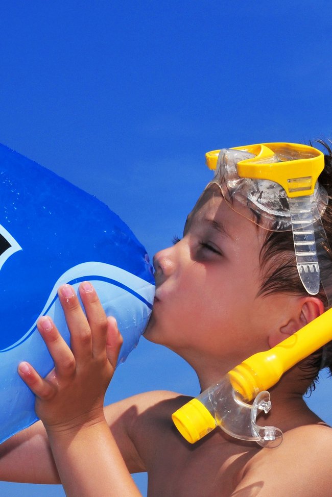 Junge spielt mit einem aufblasbaren Wal im Wasser.